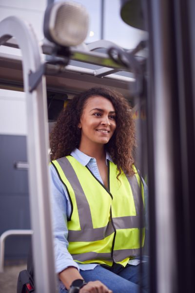 Female Worker Operating Fork Lift Truck At Freight Haulage Business